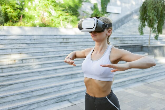 Mulher de fitness com capacete de vr, exercício ao ar livre. Aptidão de realidade virtual. Tecnologias modernas