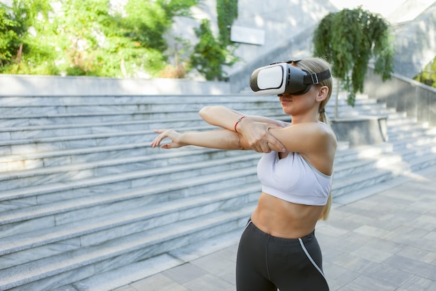 Mulher de fitness com capacete de vr, exercício ao ar livre. Aptidão de realidade virtual. Tecnologias modernas