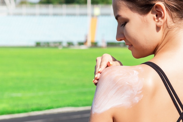 Mulher de fitness é aplicar protetor solar no ombro