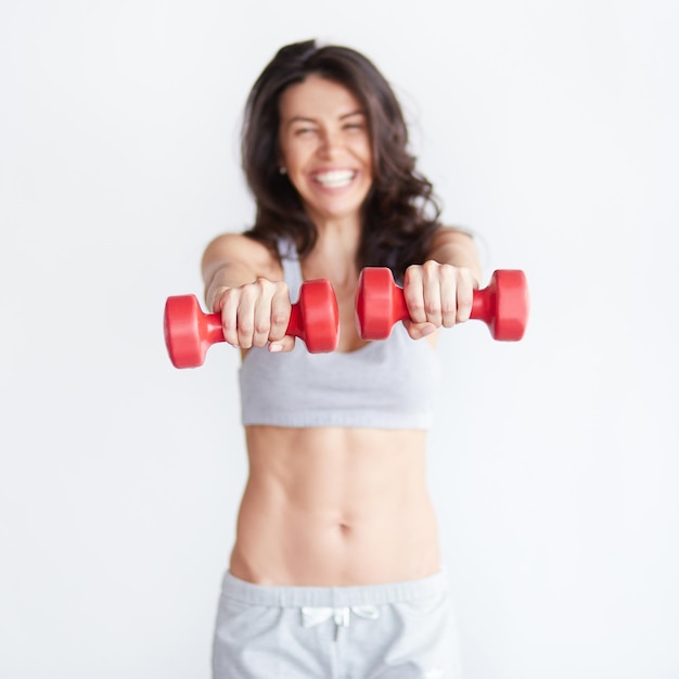 Mulher de fitness feliz levantando halteres sorrindo alegre