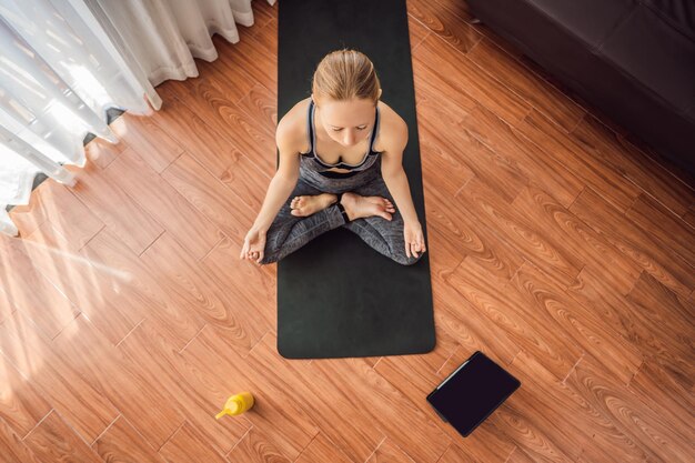 Mulher de fitness se exercitando no chão em casa e assistindo vídeos de fitness em um tablet que as pessoas fazem