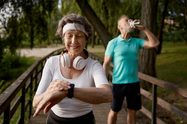 Mulher de fitness sênior orgulhosa de ultrapassar seu marido cansado durante o treino matinal de corrida aposentado cardio bem-estar ou maratona jog