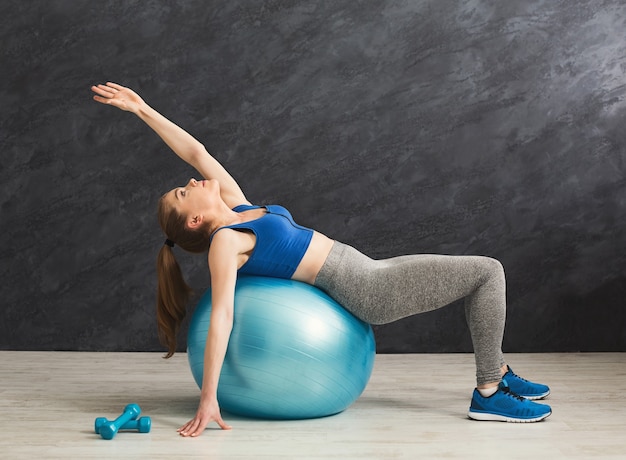 Foto mulher de fitness treinando com bola de fitness no ginásio. jovem magro fazendo exercícios aeróbicos, copie o espaço. estilo de vida saudável, conceito de ginástica