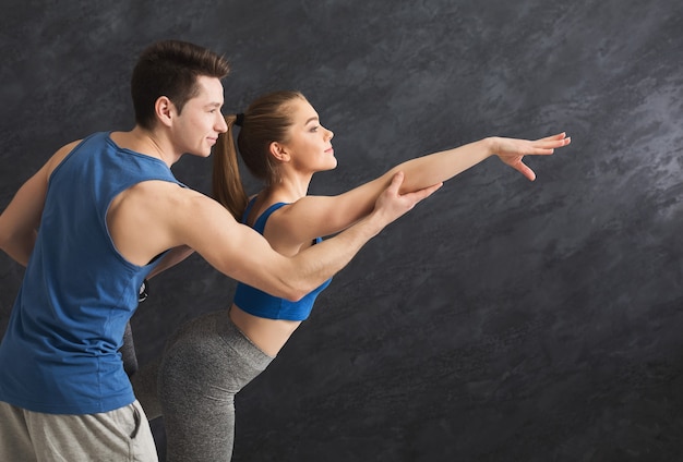 Mulher de fitness treinando com seu personal trainer na academia. casal jovem fazendo exercícios de alongamento, copie o espaço