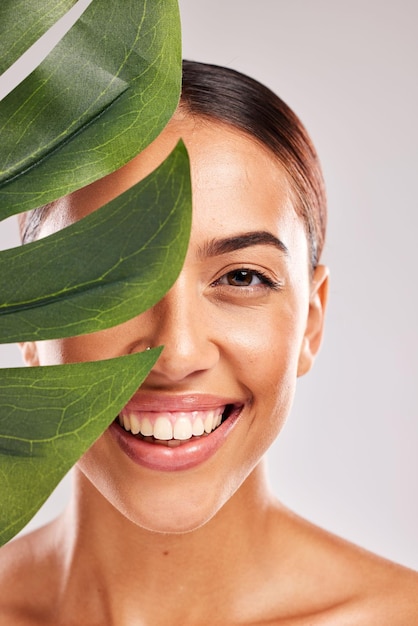 Mulher de folha e beleza cuidados com a pele naturais e cosméticos limpos para brilho de bem-estar e sustentabilidade no fundo do estúdio Retrato de rosto de modelo feliz folhas verdes de monstera e dermatologia de plantas ecológicas