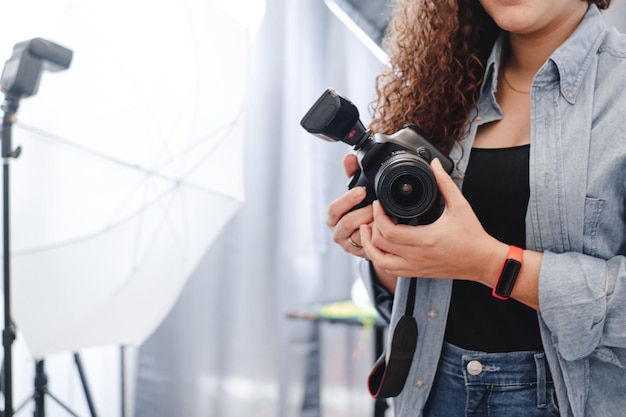 Mulher de fotógrafo desconhecido segurando uma câmera profissional no estúdio