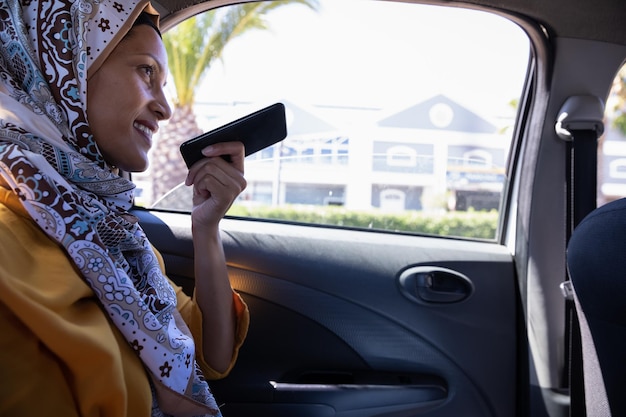 Mulher de hijab a falar ao telemóvel no carro