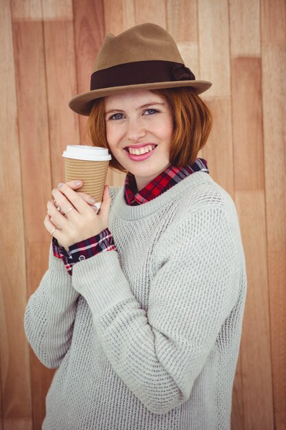 mulher de hipster sorridente em um chapéu, segurando um café