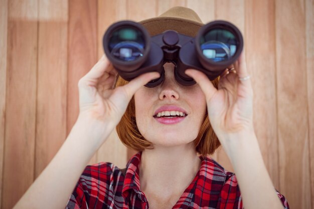 mulher de hipster sorridente, olhando através de binóculos