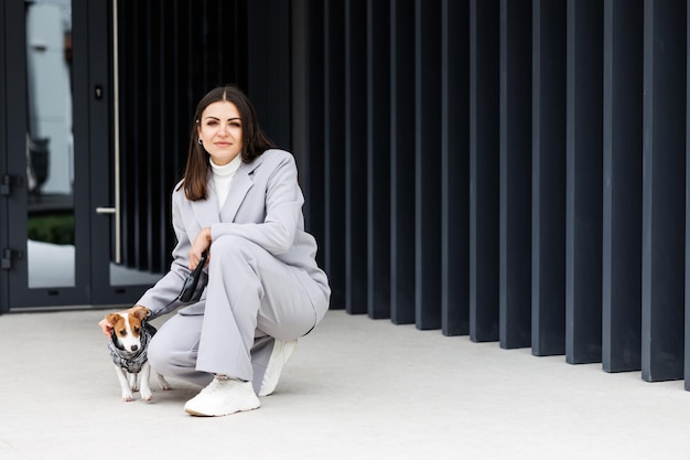 Mulher de jaqueta casual sentada perto de seu cão de raça pura Jack Russell Terrier fofo treinado