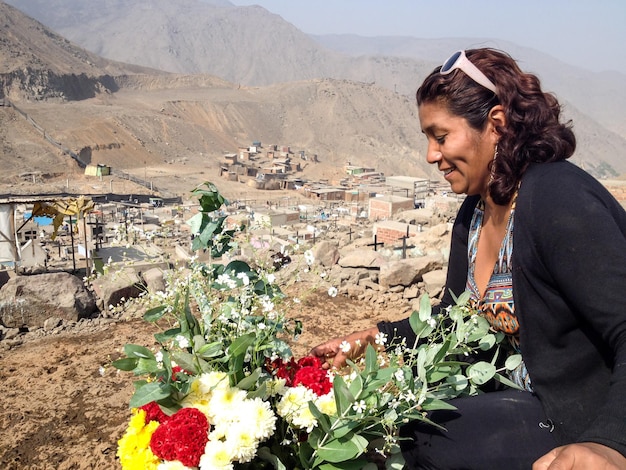 Mulher de jardineiro organizando flores em um cemitério