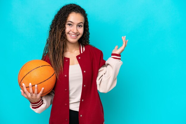 Mulher de jogador de basquete árabe isolada em fundo azul, estendendo as mãos para o lado para convidar para vir