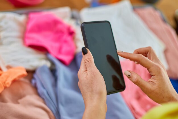 Foto mulher de mão irreconhecível fazendo mala verifica as coisas no smartphone