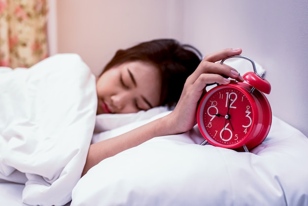 mulher de mão segurando o alarme do relógio vermelho