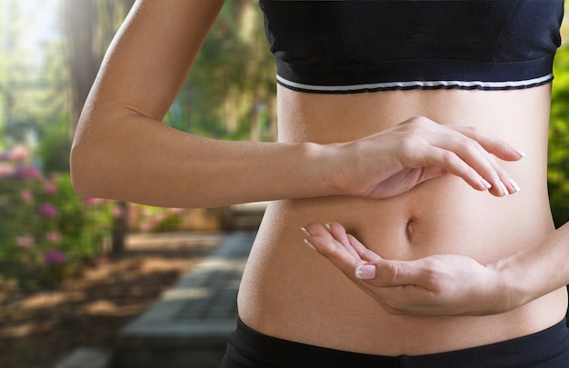 Foto mulher de mãos dadas com gesto de proteção perto da barriga