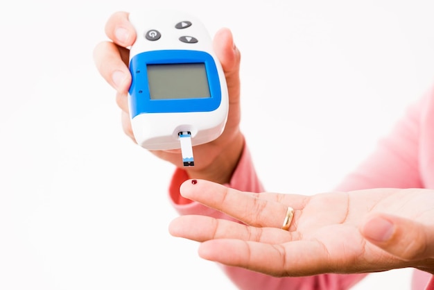 Foto mulher de mãos medindo a verificação do nível de teste de glicose com sangue no dedo pelo glicosímetro