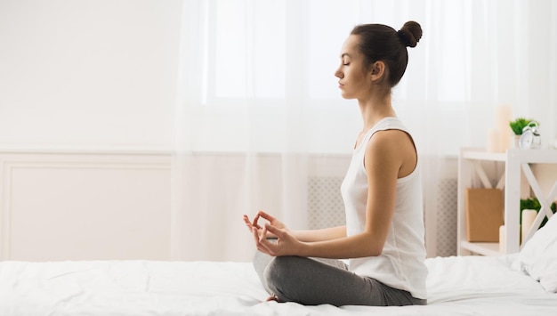 Mulher de meditação matinal praticando ioga na cama