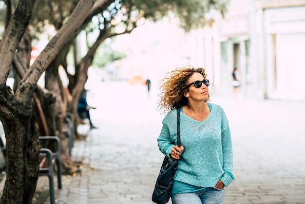 Mulher de meia idade andando no parque ao ar livre da cidade sorrindo feliz Roupa casual suéter azul mulheres em atividade de lazer para fazer compras