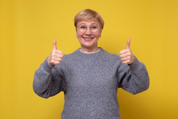 Mulher de meia idade aprova mostrando gesto positivo com os polegares da mão para cima