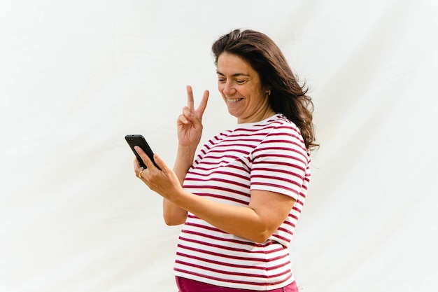 Mulher de meia-idade com cabelos longos usando smartphone em fundo claro