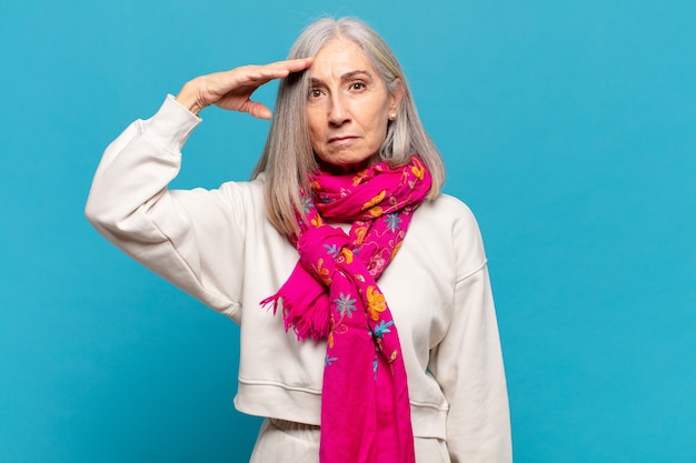 Foto mulher de meia-idade cumprimentando a câmera com uma saudação militar em um ato de honra e patriotismo, mostrando respeito