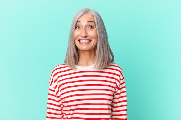 Mulher de meia-idade de cabelo branco parecendo feliz e agradavelmente surpresa