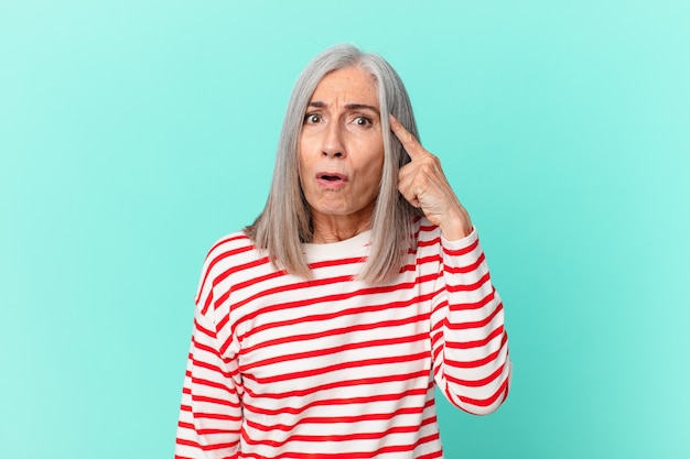 Mulher de meia-idade de cabelo branco parecendo surpresa, percebendo um novo pensamento, ideia ou conceito