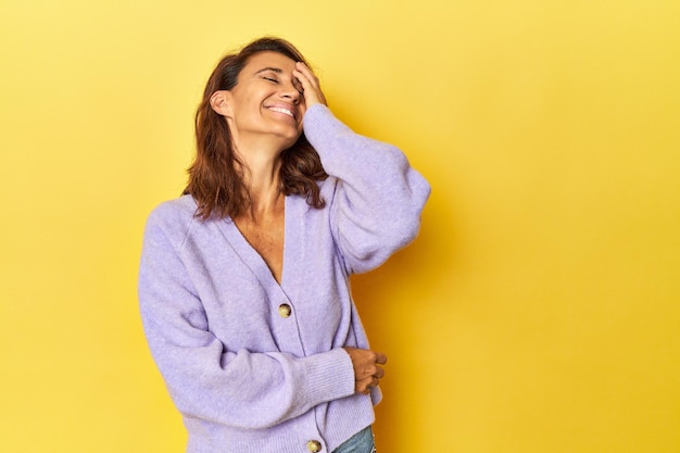 Mulher de meia idade em um pano de fundo amarelo rindo feliz emoção natural despreocupada