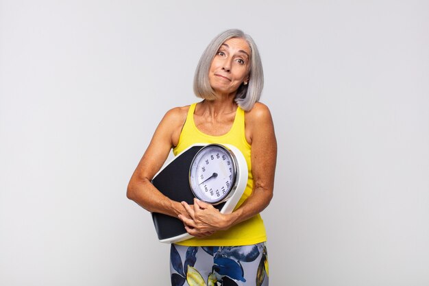 Mulher de meia-idade encolhendo os ombros, sentindo-se confusa e incerta, duvidando com os braços cruzados e olhar perplexo. conceito de fitness