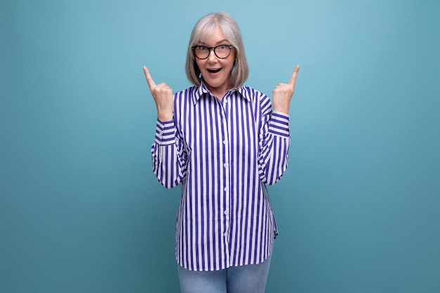 Mulher de meia-idade enérgica em uma camisa elegante em um fundo de estúdio brilhante com copyspace