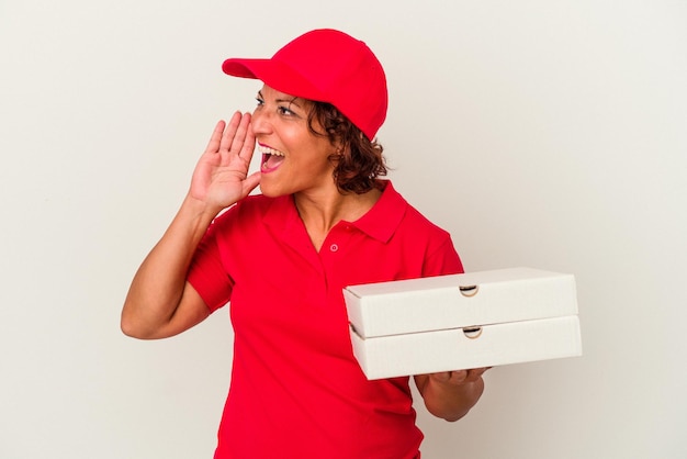 Mulher de meia-idade entregando pizzas isoladas no fundo branco, gritando e segurando a palma da mão perto da boca aberta.