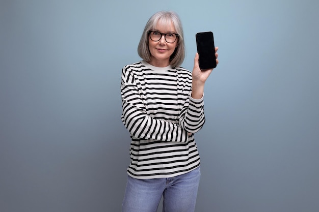 Mulher de meia idade esbelta e bem cuidada segurando um smartphone com uma maquete em um fundo brilhante