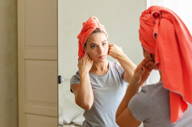 Mulher de meia idade fazendo exercícios de construção de rosto em casa massageando sua rotina de beleza de rosto Spa wellness skincare Mulher fazendo autocuidado de rotina no espelho cuidando da pele facial por massagem