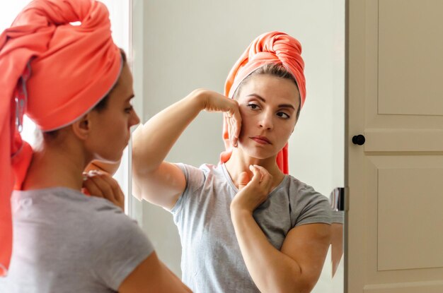 Mulher de meia idade fazendo exercícios de construção de rosto em casa massageando sua rotina de beleza de rosto Spa wellness skincare Mulher fazendo autocuidado de rotina no espelho cuidando da pele facial por massagem