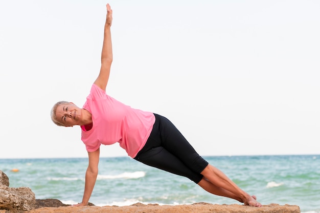 Mulher de meia idade fazendo pilates na praia.