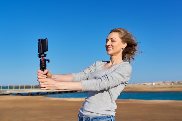 Mulher de meia idade gravando vídeo em smartphone com outdoor na beira-mar