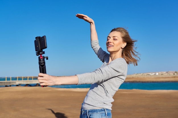 Mulher de meia idade gravando vídeo em smartphone com outdoor na beira-mar