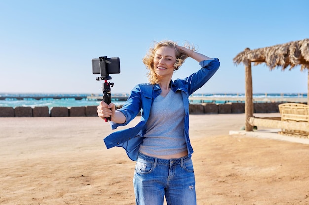 Foto mulher de meia idade gravando vídeo no smartphone férias no mar natureza marinha fundo