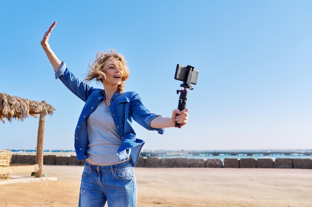 Mulher de meia idade gravando vídeo no smartphone férias no mar natureza marinha fundo