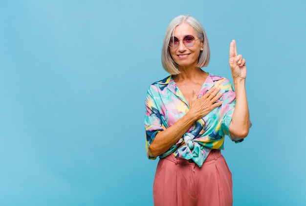 Mulher de meia-idade legal, parecendo feliz, confiante e confiável, sorrindo e mostrando sinal de vitória, com uma atitude positiva