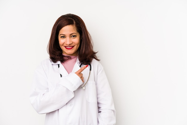 Mulher de meia-idade médico latino isolada sorrindo e apontando de lado, mostrando algo no espaço em branco.