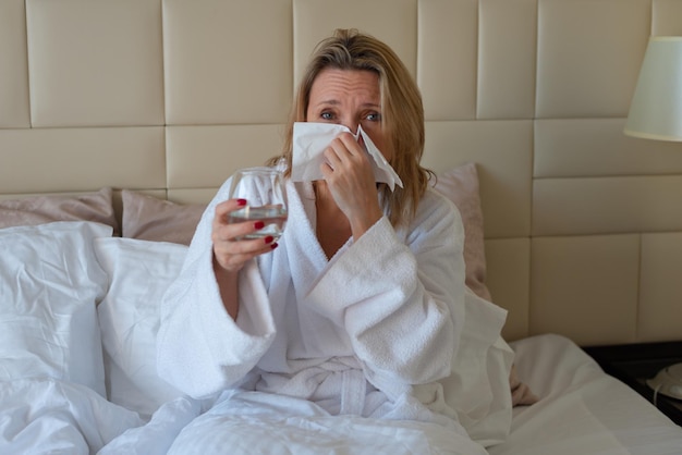 Mulher de meia idade na cama se sente mal, tem um resfriado