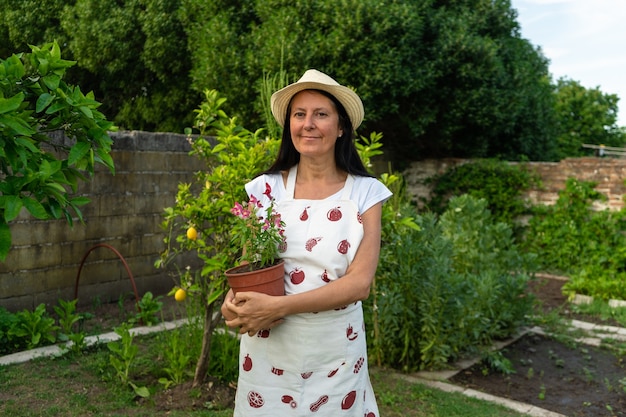 Mulher de meia-idade no jardim segurando um vaso de flores