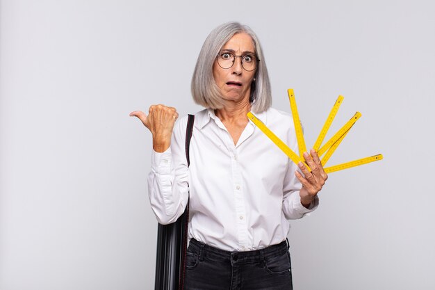 Mulher de meia-idade parecendo espantada em descrença, apontando para o objeto ao lado e dizendo uau, inacreditável. conceito de arquiteto