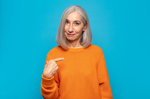 mulher de meia-idade parecendo orgulhosa, confiante e feliz, sorrindo e apontando para si mesma ou fazendo o primeiro sinal