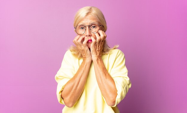 Mulher de meia-idade parecendo preocupada, ansiosa, estressada e com medo, roendo as unhas e olhando para o espaço da cópia lateral