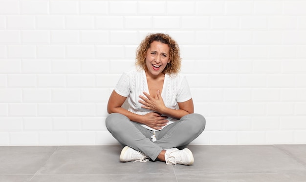 Foto mulher de meia-idade rindo alto de uma piada hilária, sentindo-se feliz e alegre, se divertindo