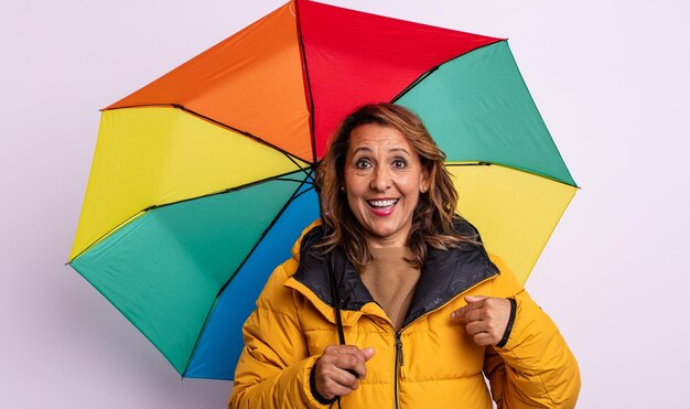 Mulher de meia idade se sentindo feliz e apontando para si mesma com um conceito de guarda-chuva animado