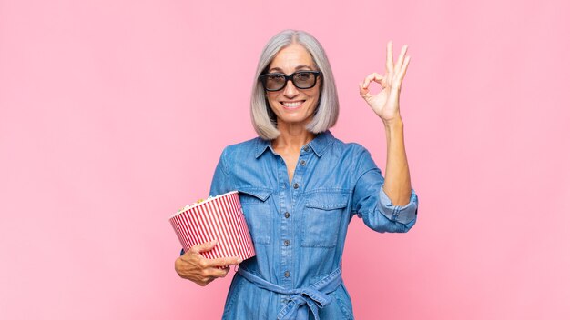 Mulher de meia-idade se sentindo feliz, relaxada e satisfeita, mostrando aprovação com um gesto de ok, sorrindo conceito de filme