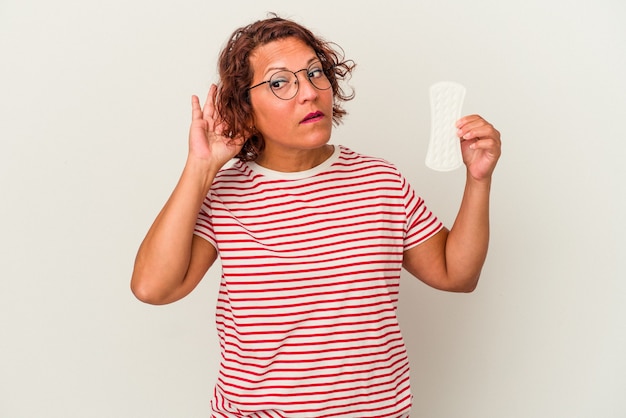 Mulher de meia idade segurando uma compressa isolada no fundo branco, tentando ouvir uma fofoca.